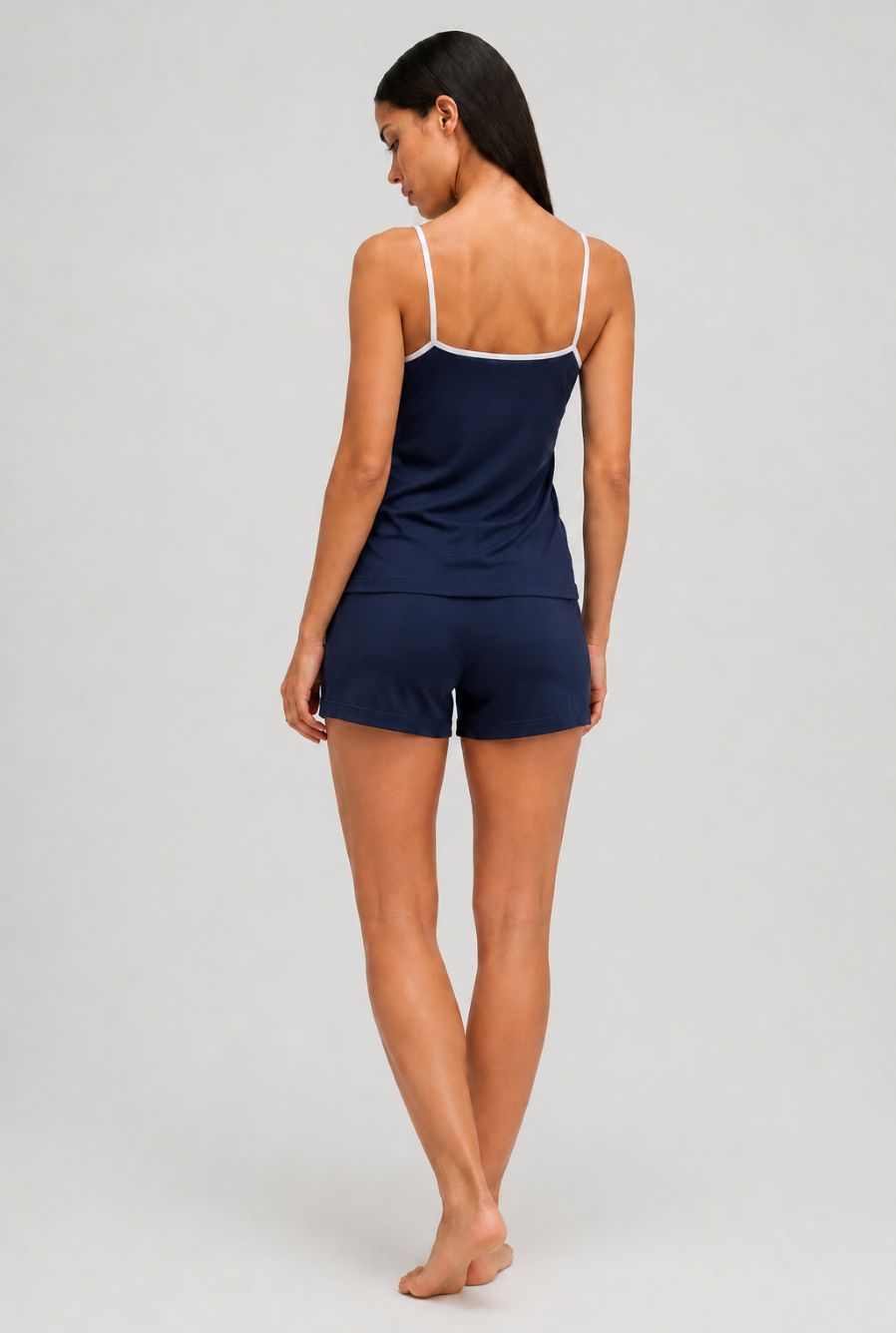 Modelo usando pijama feminino conjunto aurora azul marinho com blusa de alças e short com cordão em vista traseira