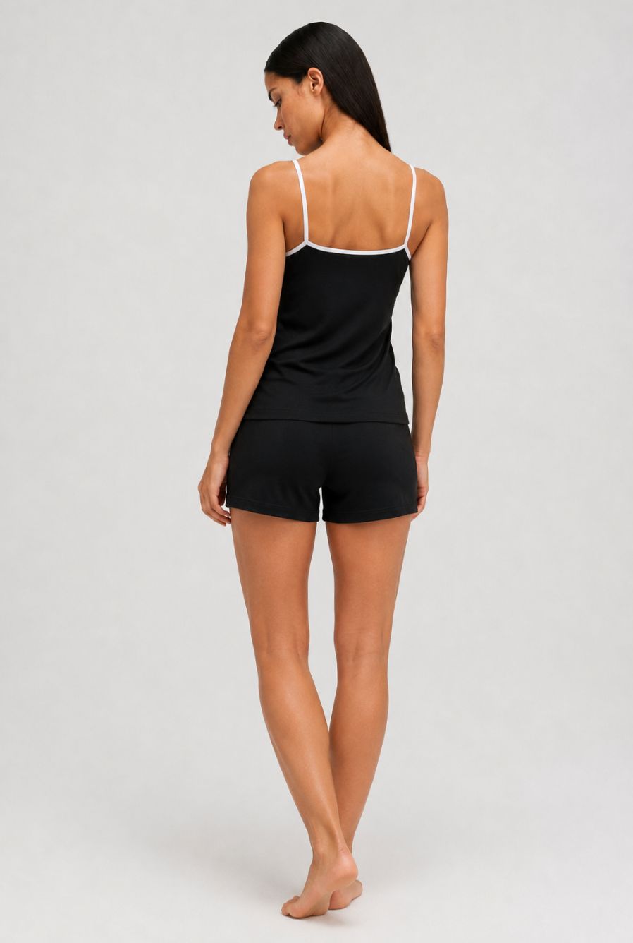 Modelo usando pijama feminino conjunto aurora preto com blusa de alças e short com cordão em vista traseira