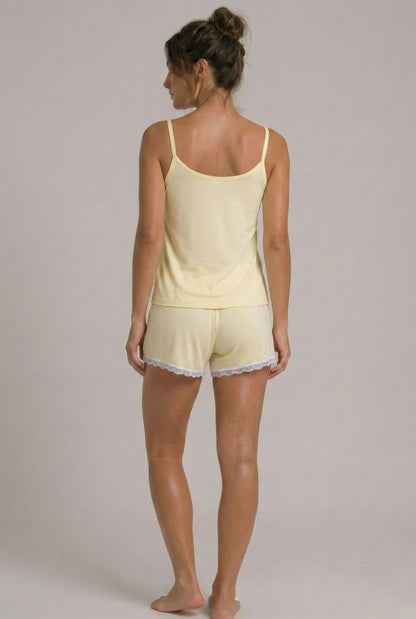 Modelo usando pijama feminino conjunto Veneza amarelo com blusa de alças, short e detalhe em renda branca em vista traseira
