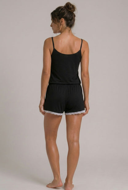 Modelo usando pijama feminino conjunto Veneza preto com blusa de alças, short e detalhe em renda branca em vista traseira